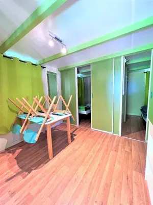 a room with a table and chairs on a wooden floor at CAMPING LES ILOTS D'OR in Porto-Vecchio