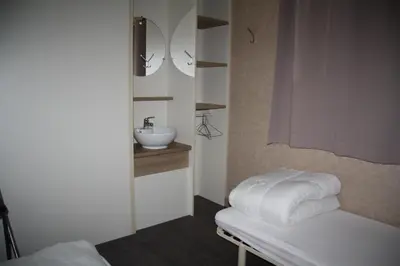a bathroom with a sink and a white bench with towels at CAMPING LES ILOTS D'OR in Porto-Vecchio
