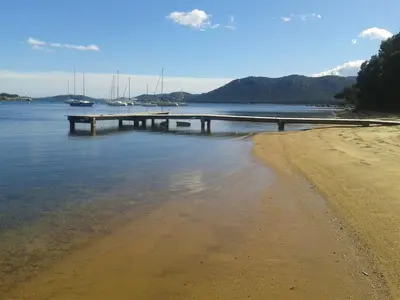 a dock in the water next to a beach at CAMPING LES ILOTS D'OR in Porto-Vecchio