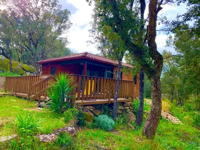 a cabin in the woods with a wrap around deck at L'Aravone Lodge in Sartène