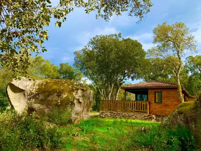 a log cabin with a large rock in the yard at L'Aravone Lodge in Sartène