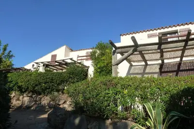 a white building with a wooden pergola at Bellavistaloc' in Porto-Vecchio