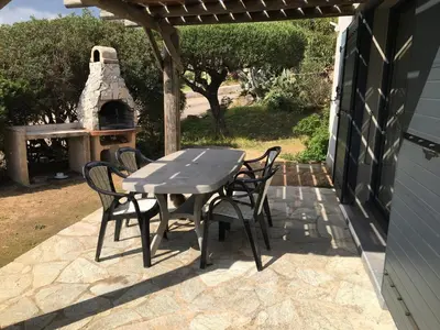 a table and chairs on a patio with a pizza oven at Bellavistaloc' in Porto-Vecchio