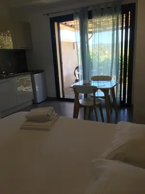 a bedroom with a bed and a table and a kitchen at Bellavistaloc' in Porto-Vecchio