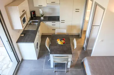 a kitchen with a table and chairs in a room at Bellavistaloc' in Porto-Vecchio
