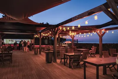 a restaurant with wooden tables and chairs and lights at Belambra Clubs Borgo - Pineto in Borgo