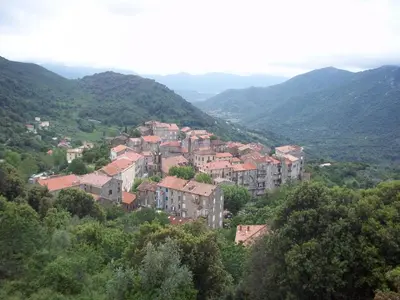 a group of buildings on a hill with mountains at Le Chalet de Valentine & Laurent in Olmiccia