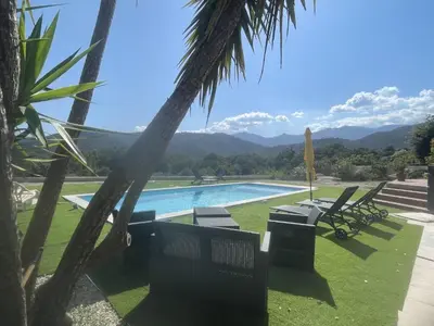 a pool with chairs and a view of the mountains at House Angeli in Prunelli-di-Fiumorbo