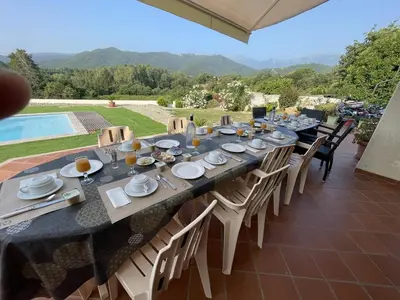 a table set for a meal on a patio with a pool at House Angeli in Prunelli-di-Fiumorbo