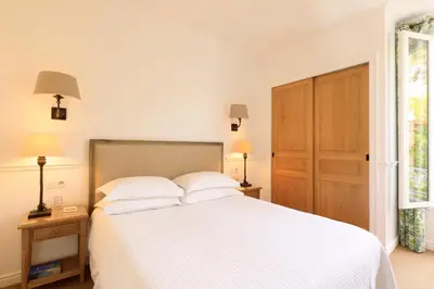 a bedroom with a white bed with two lamps and a door at Hôtel Les Mouettes - Teritoria in Ajaccio