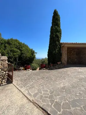 a stone patio with a tree in front of a house at Maison En Pierre Corse Vue Mer in Sari Solenzara