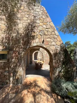 an archway in a stone building with a table at Maison En Pierre Corse Vue Mer in Sari Solenzara