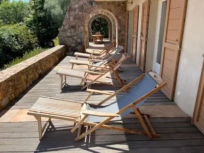 a row of lounge chairs sitting on a porch at Maison En Pierre Corse Vue Mer in Sari Solenzara
