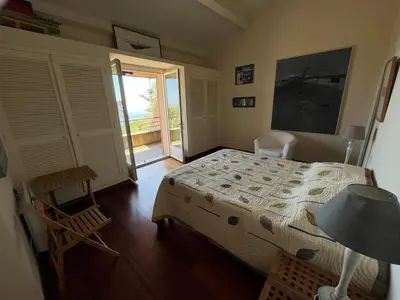 a bedroom with a bed and a door to a balcony at Maison En Pierre Corse Vue Mer in Sari Solenzara
