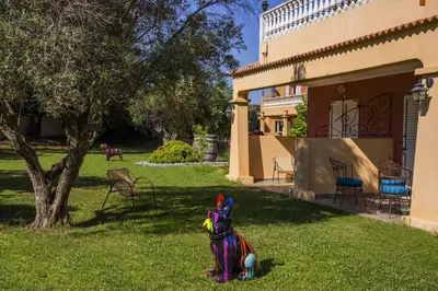 a toy dog sitting in the grass next to a building at Hotel du Pont de l'Oso in Cala Rossa