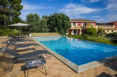 a swimming pool with chairs and an umbrella at Hotel du Pont de l'Oso in Cala Rossa
