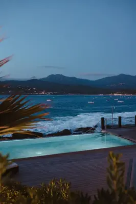 a swimming pool with the ocean in the background at Hôtel Castel d'Orcino in Calcatoggio