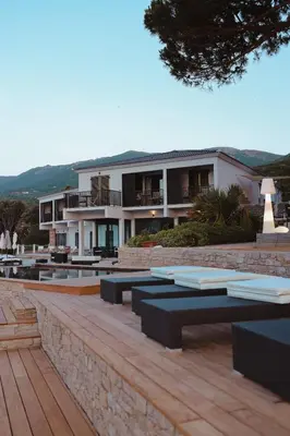 a building with benches and tables in front of it at Hôtel Castel d'Orcino in Calcatoggio