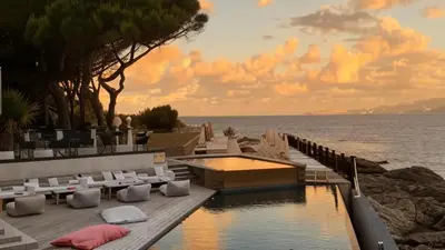 a resort with a pool and a body of water at Hôtel Castel d'Orcino in Calcatoggio