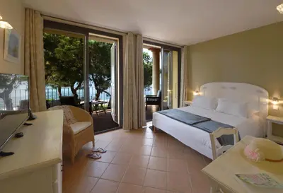 a bedroom with a bed and a living room at Hôtel Castel d'Orcino in Calcatoggio