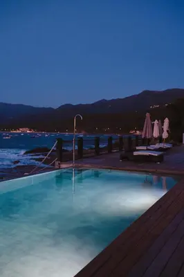 a large swimming pool with a view of the water at Hôtel Castel d'Orcino in Calcatoggio