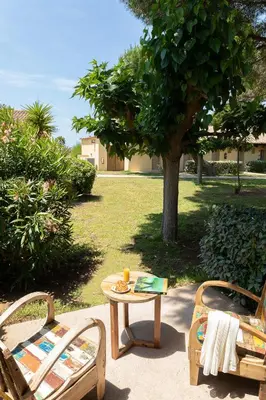 a table and two chairs and a table and a tree at Hôtel-Restaurant Marina Di Lava - Grand Ajaccio in Appietto