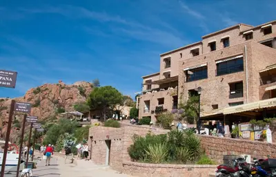 a brick building with a mountain in the background at Hôtel & Restaurant Le Belvédère in Porto Ota