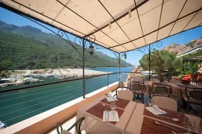 a balcony with tables and chairs and a view of the water at Hôtel & Restaurant Le Belvédère in Porto Ota