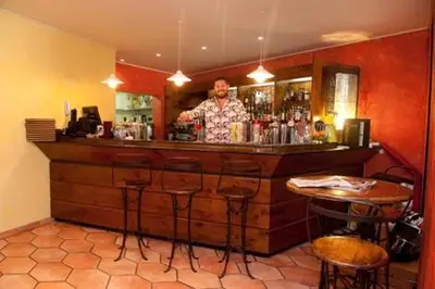 a man standing behind a bar in a restaurant at Hôtel & Restaurant Le Belvédère in Porto Ota