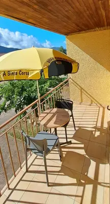 a patio with a table and a yellow umbrella at Scopa Rossa in Evisa