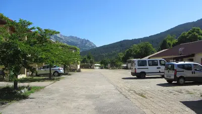 a parking lot with two cars parked next to buildings at Scopa Rossa in Evisa