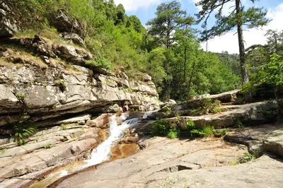 a waterfall on the side of a rocky mountain at Scopa Rossa in Evisa