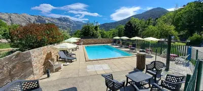 a swimming pool with chairs and umbrellas in front of mountains at Scopa Rossa in Evisa