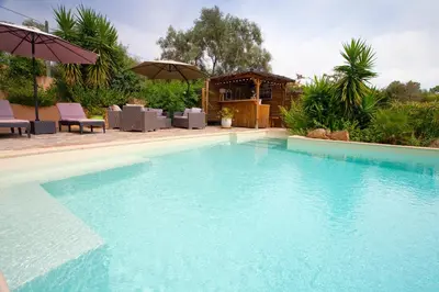 a large blue swimming pool with chairs and umbrellas at Villa Mimosa in Favone