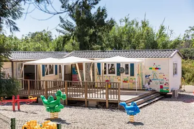 a tiny house with a playground and surfboards at Camping Acqua E Sole in Sainte-Lucie de Porto-Vecchio