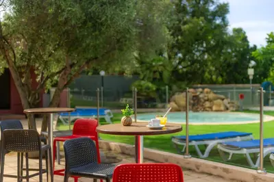 a patio with tables and chairs and a playground at Camping Acqua E Sole in Sainte-Lucie de Porto-Vecchio