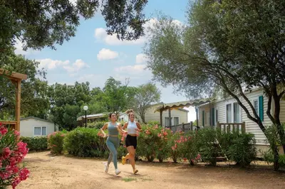 two women walking in front of a house at Camping Acqua E Sole in Sainte-Lucie de Porto-Vecchio