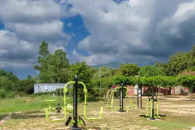a playground with yellow play equipment in a park at Camping Acqua E Sole in Sainte-Lucie de Porto-Vecchio
