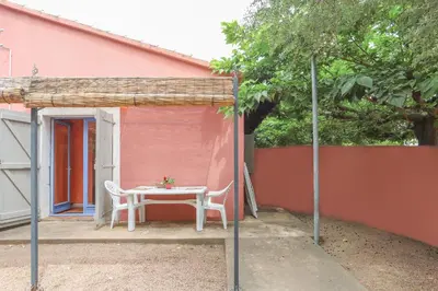 a table and chair in front of a pink house at Camping Acqua E Sole in Sainte-Lucie de Porto-Vecchio