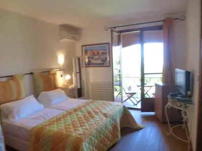 a bedroom with a bed and a television and a balcony at Auberge U Licettu in Cuttoli-Corticchiato