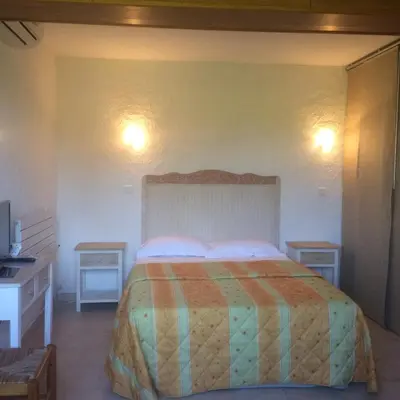 a bedroom with a bed and two tables and a television at Auberge U Licettu in Cuttoli-Corticchiato
