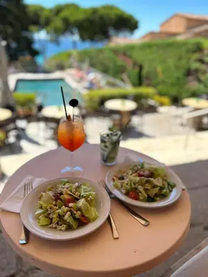 a table with two plates of food and a drink at Hôtel La Pinède in Ajaccio