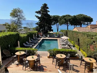 a resort with a pool and tables and chairs at Hôtel La Pinède in Ajaccio
