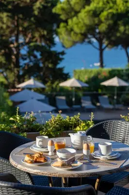 a table with plates of food and drinks on it at Hôtel La Pinède in Ajaccio
