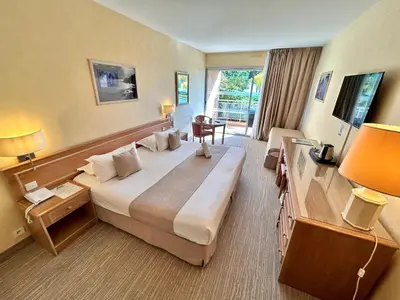 a hotel room with a large bed and a desk at Hôtel La Pinède in Ajaccio