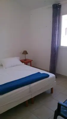 a bedroom with a bed and a window and a table at Résidence Tamaris 2 in Porto-Vecchio
