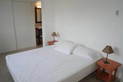a bedroom with a white bed with two night stands at Résidence Tamaris 2 in Porto-Vecchio
