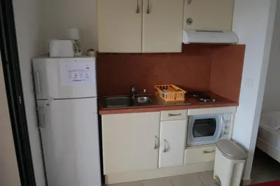 a small kitchen with a white refrigerator and a microwave at Résidence Tamaris 2 in Porto-Vecchio