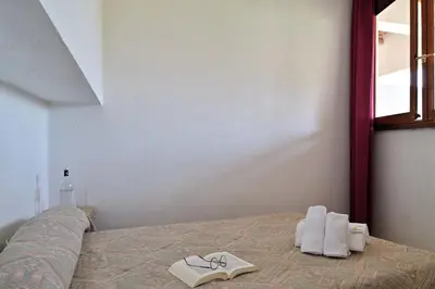 a bedroom with a bed with shoes and a book at Motel de Porticcio in Porticcio