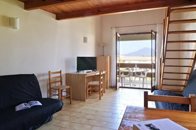 a living room with a couch and a television and a table at Motel de Porticcio in Porticcio